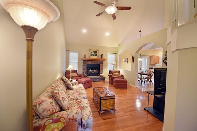 living room featuring ceiling fan, a fireplace, high vaulted ceiling, and light hardwood / wood-style floors