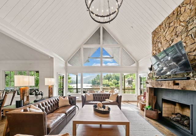 living area with a notable chandelier, a fireplace, high vaulted ceiling, and wood finished floors