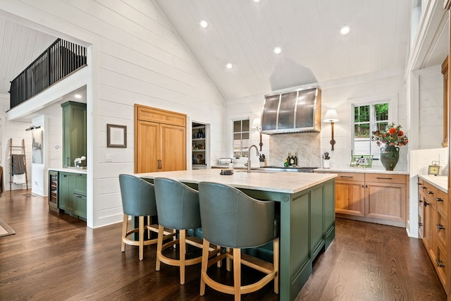 kitchen featuring an island with sink, green cabinets, dark wood finished floors, and light countertops