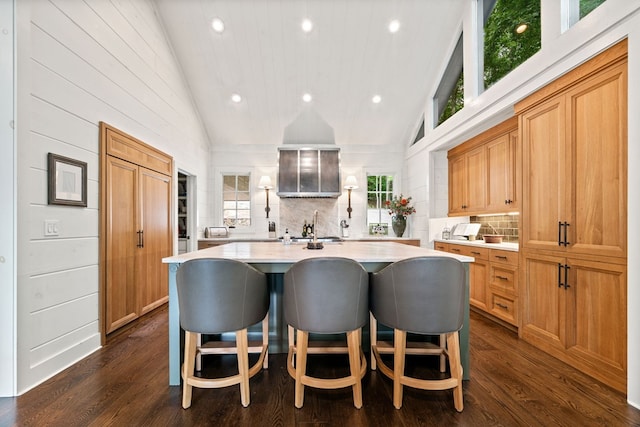 kitchen with an island with sink, dark wood-style floors, a kitchen bar, and light countertops