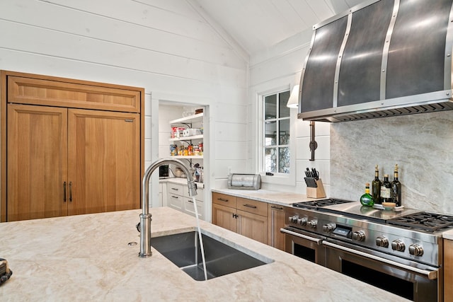 kitchen with brown cabinetry, lofted ceiling, range with two ovens, a sink, and backsplash