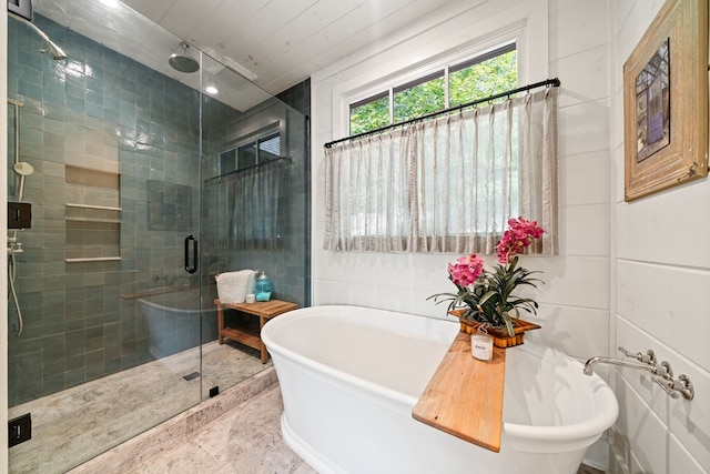 bathroom with a soaking tub, a shower stall, and tile walls