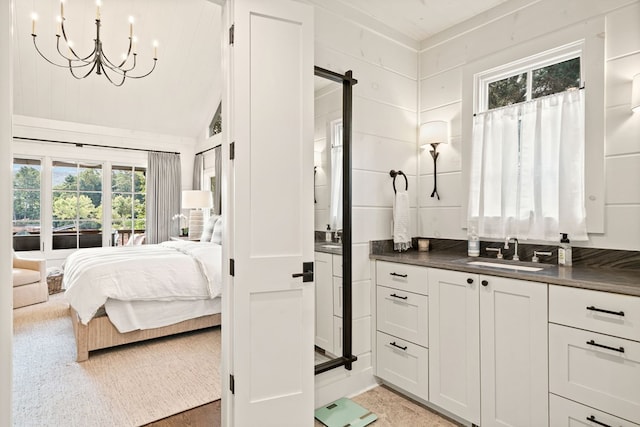 ensuite bathroom featuring a notable chandelier, connected bathroom, vanity, and lofted ceiling