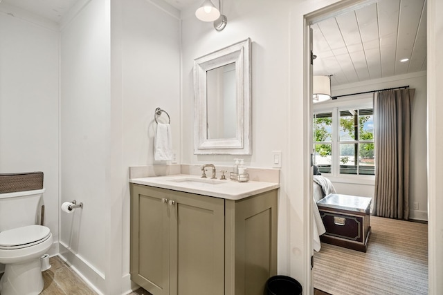 bathroom featuring baseboards, toilet, ensuite bathroom, wood finished floors, and vanity