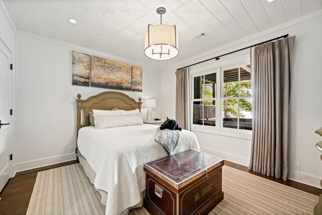 bedroom with dark wood-style floors, visible vents, baseboards, ornamental molding, and wooden ceiling