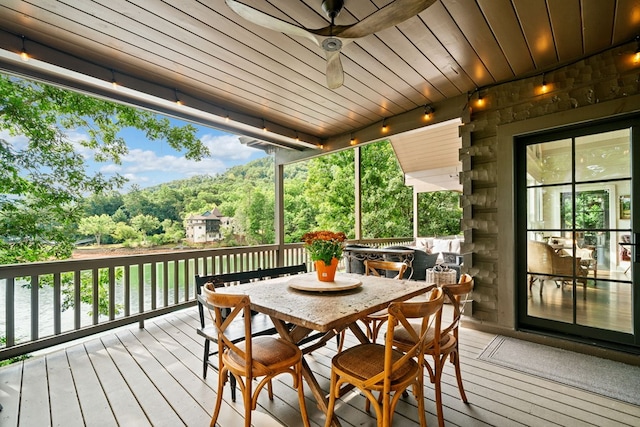 wooden terrace featuring outdoor dining area and a ceiling fan