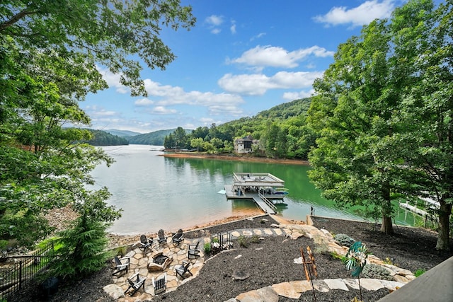 view of dock with fence, a water view, and an outdoor fire pit