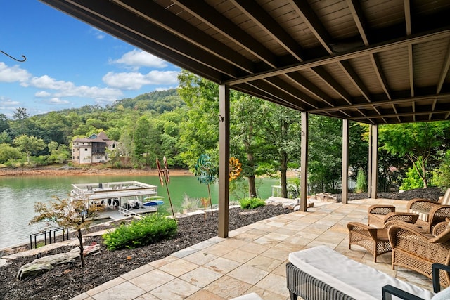 view of patio featuring a wooded view, a dock, and a water view