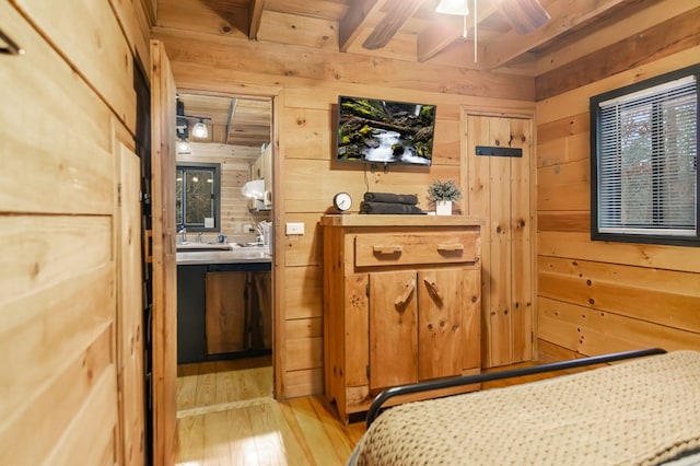 bedroom featuring light hardwood / wood-style flooring, beam ceiling, and wood walls