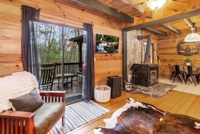 interior space with beam ceiling, wooden walls, and a wood stove