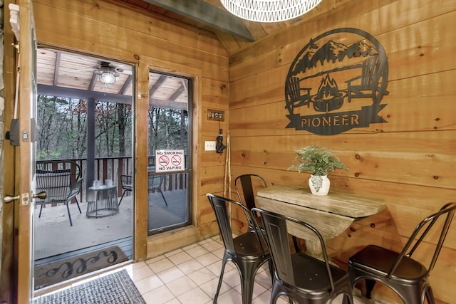 dining area featuring ceiling fan, light tile patterned floors, wood ceiling, and wooden walls