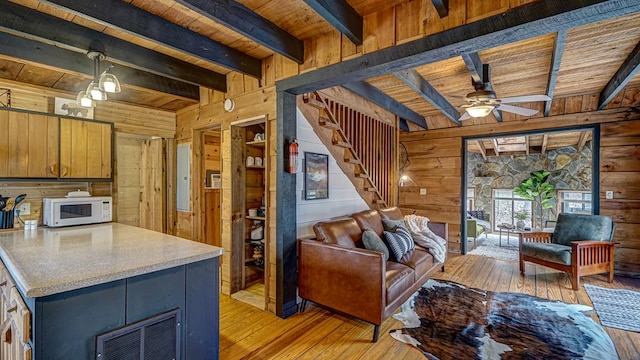 living room with wood ceiling, wooden walls, and light hardwood / wood-style flooring