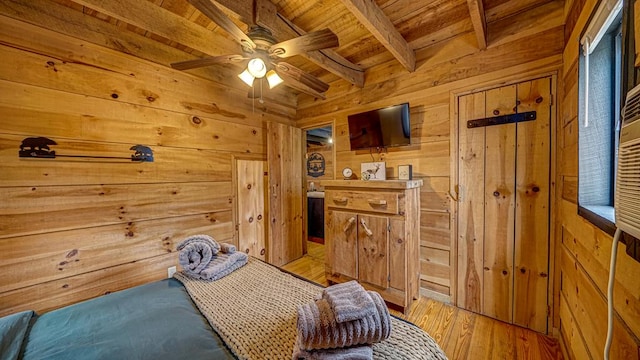 bedroom with beam ceiling, wooden walls, wooden ceiling, and light wood-type flooring