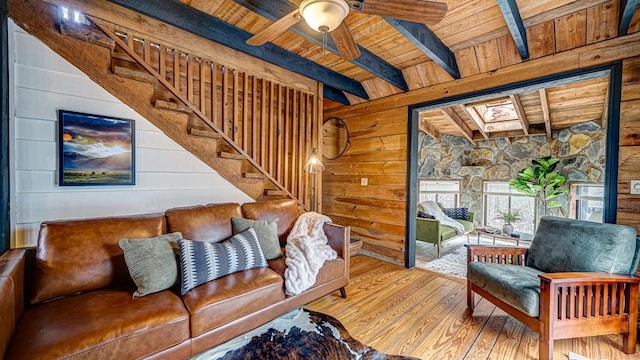 living room with wood ceiling, beamed ceiling, a skylight, and wood walls