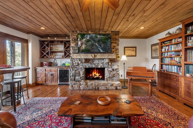 interior space with wood-type flooring, a stone fireplace, beverage cooler, and wooden ceiling