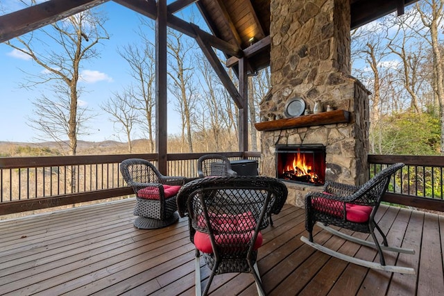 wooden deck with an outdoor stone fireplace and a mountain view