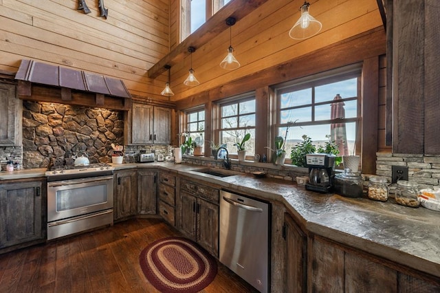 kitchen with a sink, dark wood-style flooring, wood walls, and stainless steel appliances