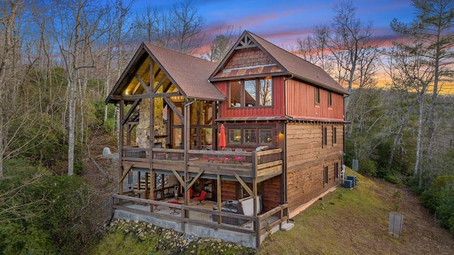 back of house at dusk featuring a deck and roof with shingles