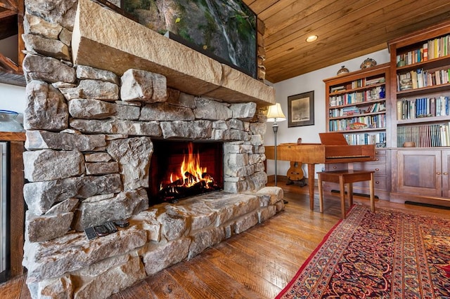 sitting room featuring a stone fireplace, wood ceiling, and hardwood / wood-style flooring
