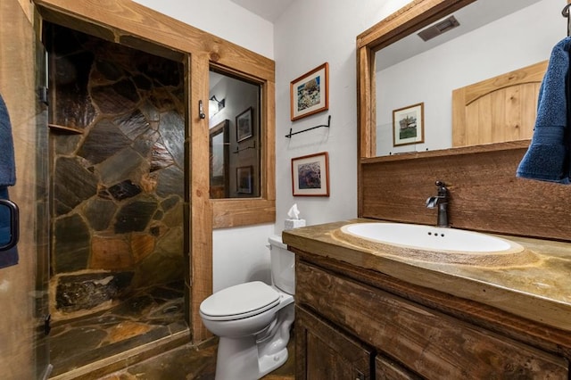bathroom with vanity, a stall shower, toilet, and visible vents