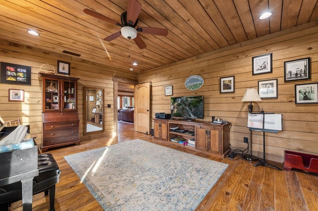 interior space with wood ceiling, wood-type flooring, a ceiling fan, and wood walls