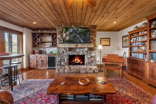 living area with hardwood / wood-style floors, beverage cooler, indoor wet bar, wood ceiling, and a ceiling fan