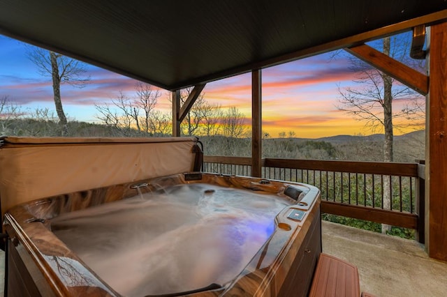 deck at dusk featuring a mountain view and a hot tub