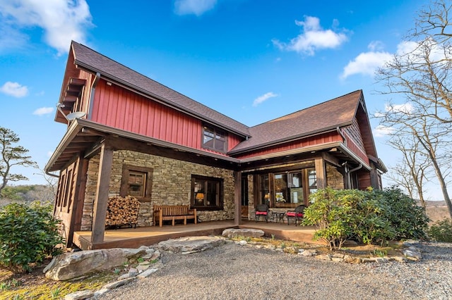 view of front of house featuring a shingled roof, a patio area, and stone siding