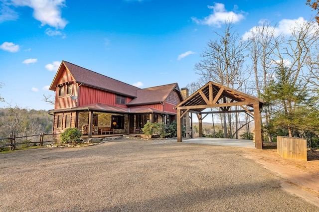 view of front of home with fence, covered porch, stone siding, a carport, and driveway