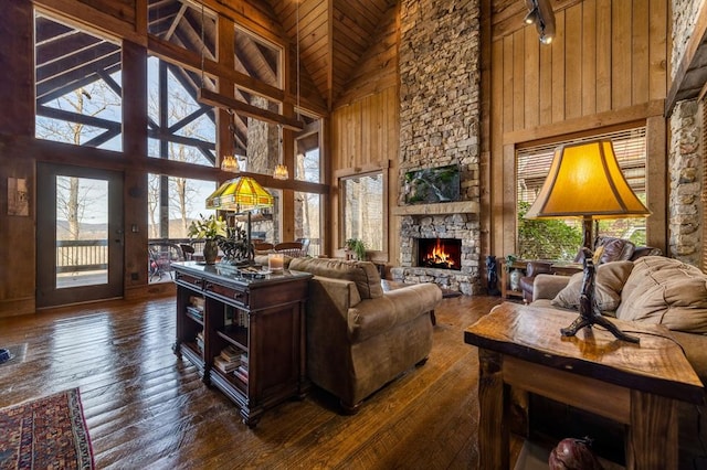 living room featuring a stone fireplace, dark wood finished floors, wood ceiling, and high vaulted ceiling
