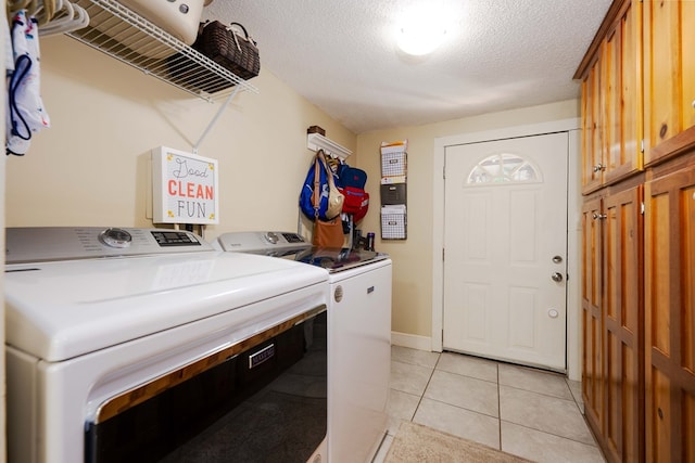 clothes washing area featuring cabinets, light tile patterned floors, separate washer and dryer, and a textured ceiling