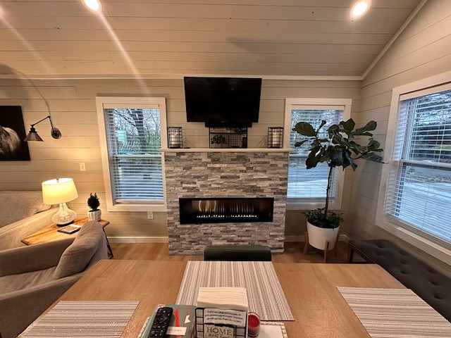 living room featuring hardwood / wood-style flooring, lofted ceiling, a stone fireplace, and plenty of natural light