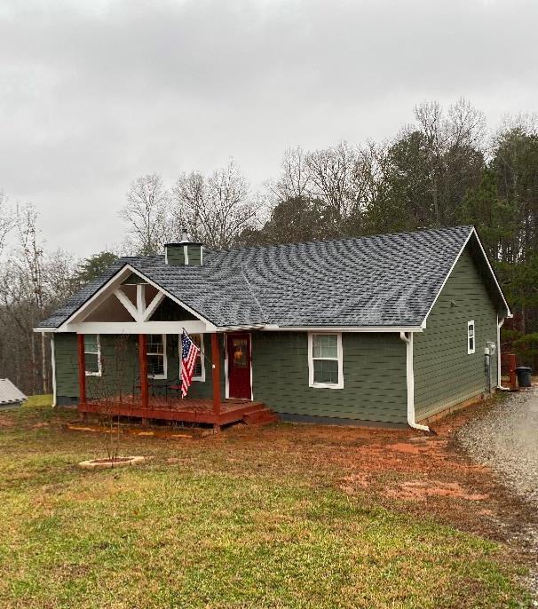 view of front of home with a front yard and roof with shingles