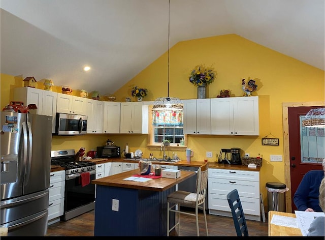 kitchen featuring a kitchen island, appliances with stainless steel finishes, butcher block countertops, decorative light fixtures, and white cabinetry