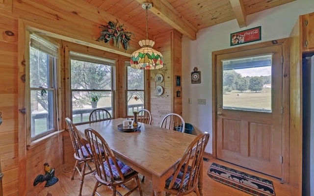 dining area featuring light wood-type flooring, beamed ceiling, wood walls, and wooden ceiling