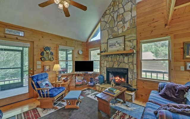 living room featuring a healthy amount of sunlight, a stone fireplace, and high vaulted ceiling