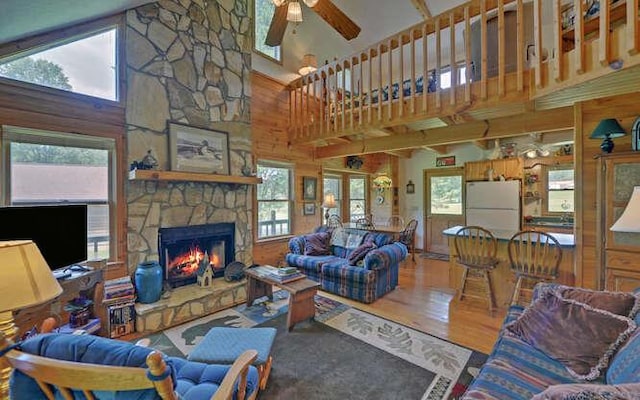 living room featuring a fireplace, wood finished floors, a wealth of natural light, and a ceiling fan