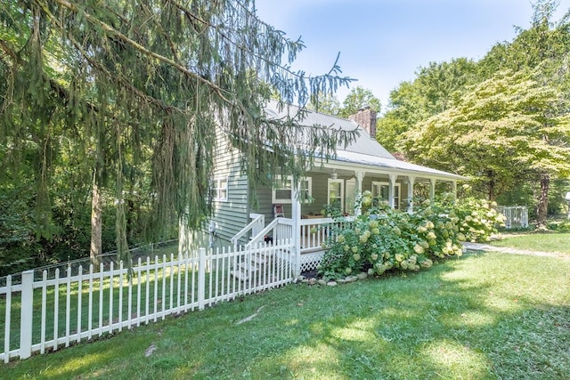 view of front of property featuring a front lawn, fence, covered porch, and a chimney