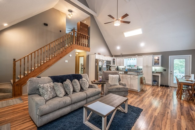 living area featuring stairway, light wood-style flooring, high vaulted ceiling, and ceiling fan