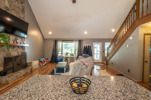 living area featuring stairway, a fireplace, baseboards, and wood finished floors