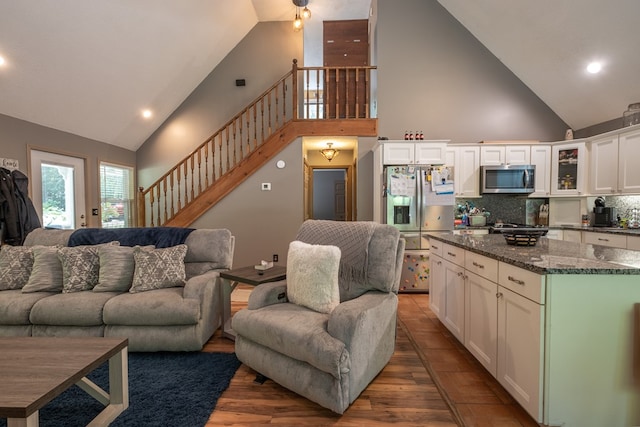 living area featuring stairs, recessed lighting, wood finished floors, and high vaulted ceiling