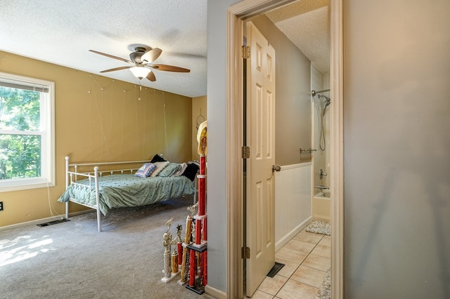 bedroom featuring light tile patterned floors, a ceiling fan, visible vents, a textured ceiling, and light colored carpet