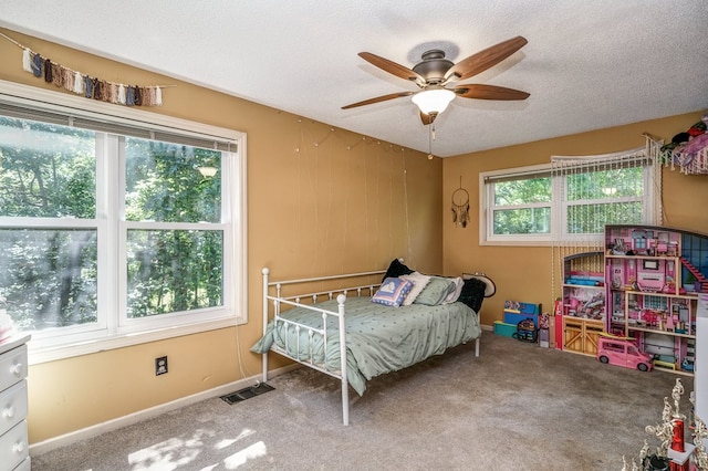 bedroom featuring visible vents, baseboards, ceiling fan, carpet flooring, and a textured ceiling