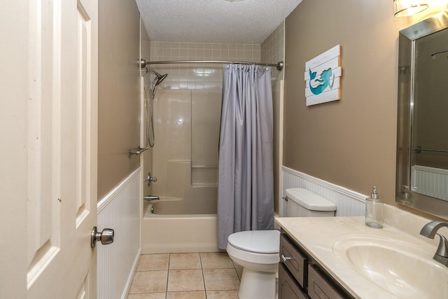 bathroom featuring a wainscoted wall, toilet, vanity, tile patterned floors, and a textured ceiling