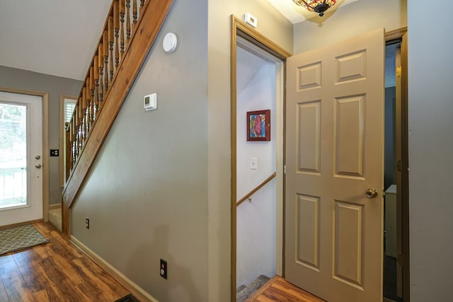 foyer entrance featuring stairs, wood finished floors, and baseboards