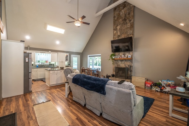 living area with visible vents, a ceiling fan, wood finished floors, and a fireplace