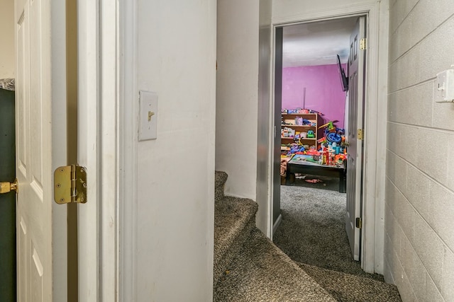 hallway with carpet flooring, stairway, and concrete block wall