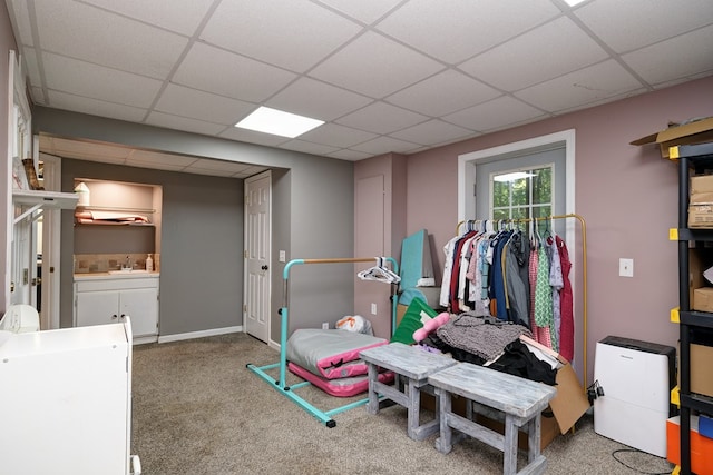 game room with carpet, baseboards, a drop ceiling, and a sink