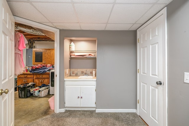 interior space with a sink, baseboards, a paneled ceiling, and washer / dryer