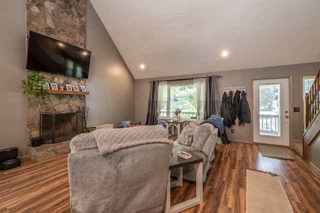 living area with baseboards, stairway, a fireplace, wood finished floors, and high vaulted ceiling